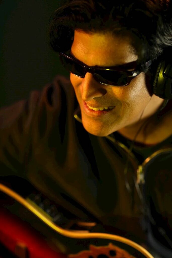 Nonviolenze AKA Shri Baratan Man Wearing Sunglasses and Playing a guitar | Eat Sleep Breathe Music