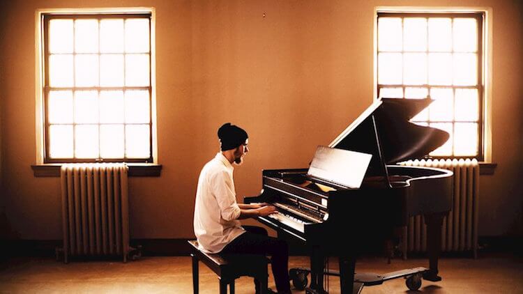 Ryan Summers Sons of Gallow Song of the Day Man In White Shirt Playing a Piano In a White Walled Apartment with a Window to the Left and Right | Eat Sleep Breathe Music