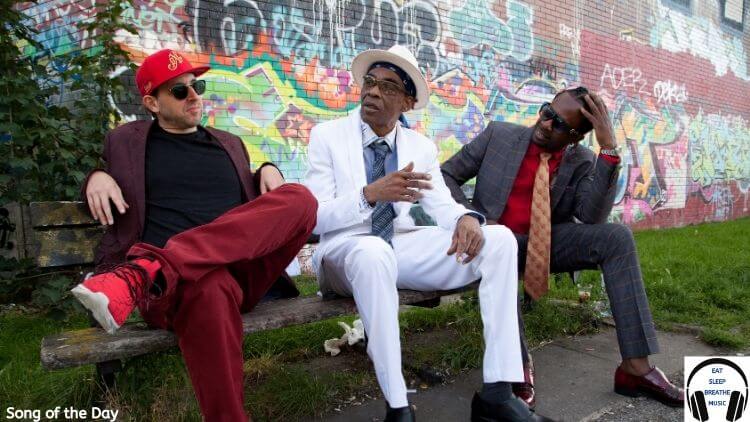 A white man, a black man and 3rd black man are sitting on a bench in suits in front of a graffiti'd wall|"Dance Without Fear" by Rebel ACA, French Monkey Wrench, Danny Sprang & iSTAND Song of the Day Feature | Eat Sleep Breathe Music