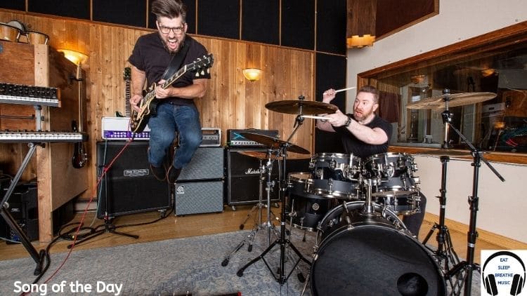 Jack and the Dull boy members Devon Summers (songwriter, guitarist, and reluctant vocalist) playing guitar and jumping in the air and drummer Aaron Nicholes sitting playing drums | Eat Sleep Breathe Music