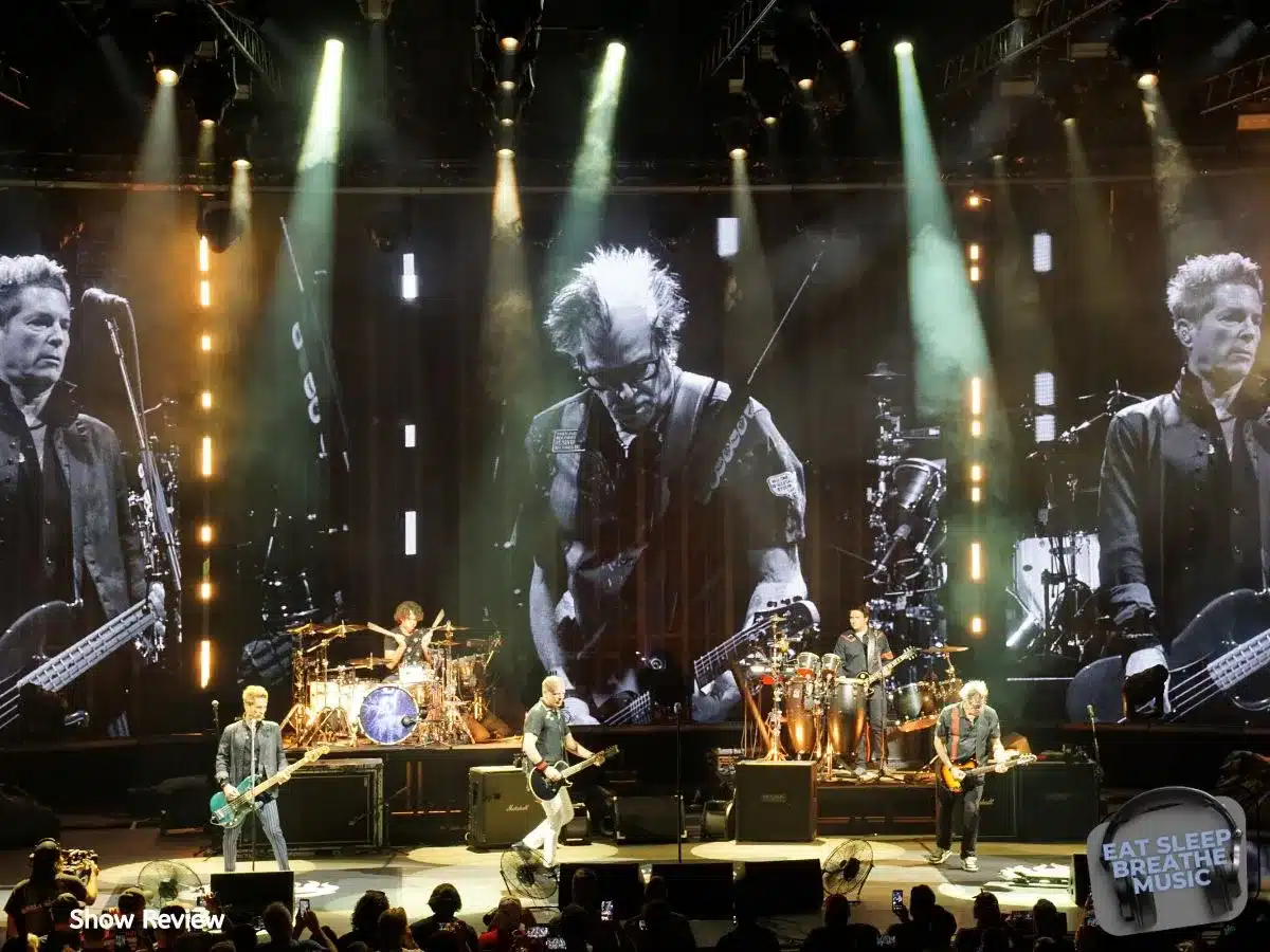 The Offspring performing live on stage at PNC Bank Arts Center with vibrant lighting and large black-and-white video projections of band members playing guitar and bass, as fans watch and take photos from the crowd | Reviews | Eat Sleep Breathe Music